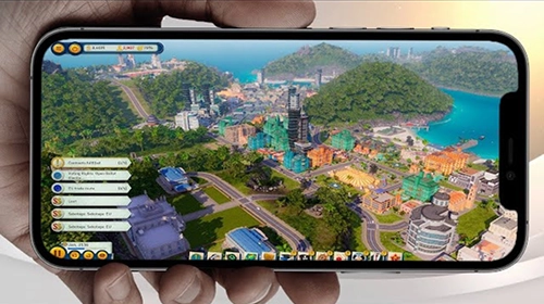 Smartphone in de hand met gameplay van een stadsbouwspel vergelijkbaar met SimCity op het scherm.